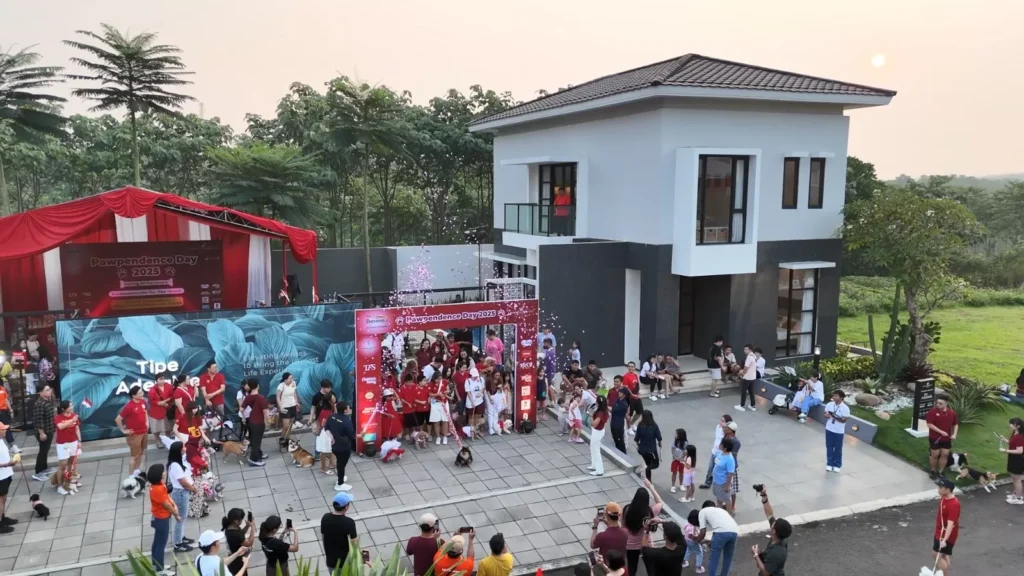 Open house PawDependence Day 2025 di CitraLand BSB City, Semarang. Tampak kerumunan orang dan hewan peliharaan di depan panggung dengan tulisan 'PawDependence Day 2025'. Acara ini diadakan di sebuah rumah contoh berarsitektur modern dengan suasana sore hari yang cerah.