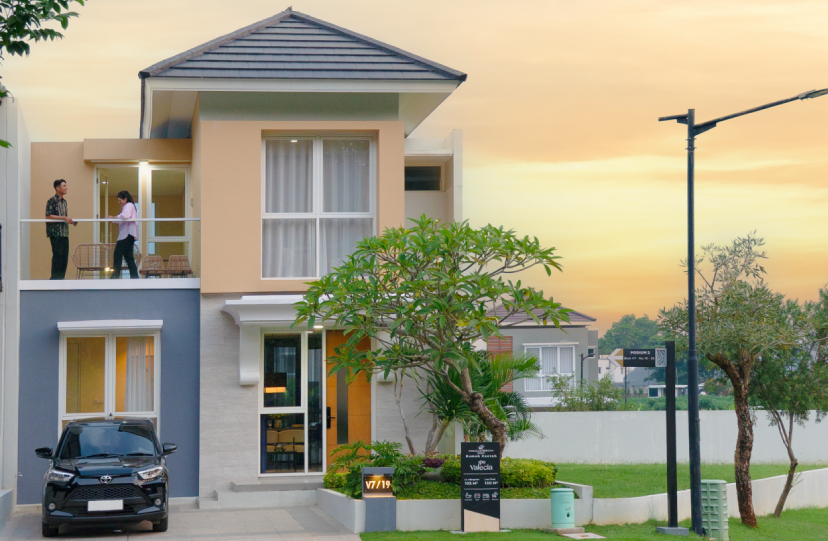 Rumah contoh Tipe Valecia di CitraLand BSB City Semarang, hunian mewah 2 lantai dengan desain modern kontemporer, memiliki balkon luas di lantai atas, carport untuk mobil, dan taman depan yang hijau di waktu senja.